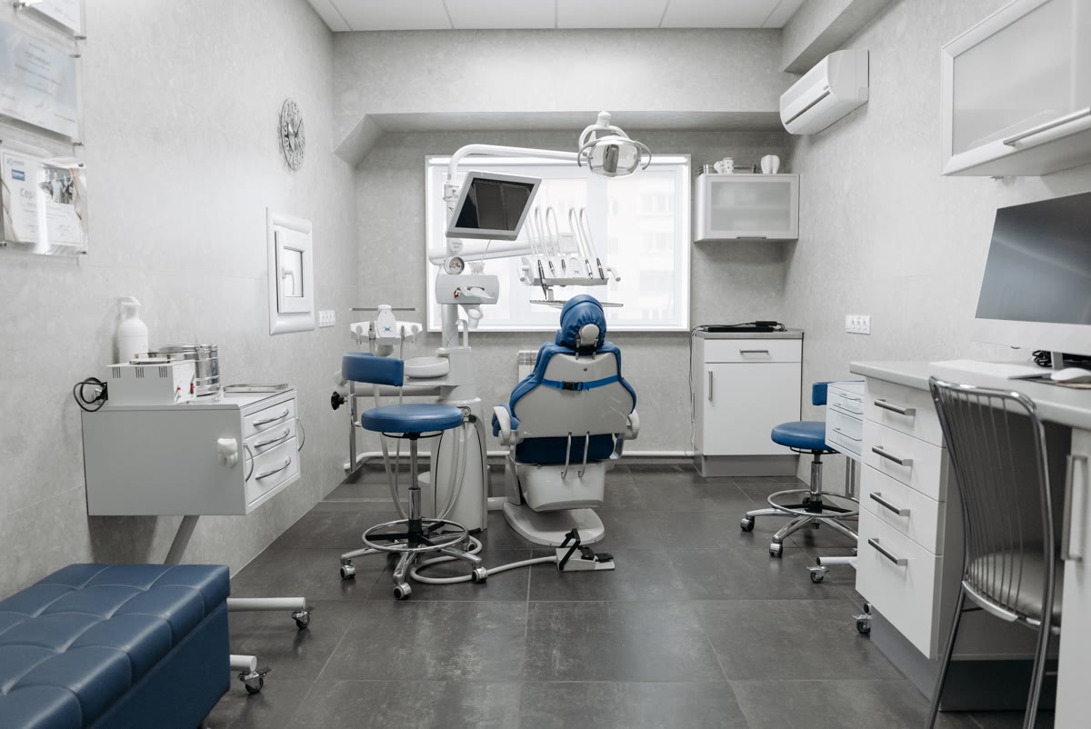 Consultório odontológico com a cadeira, os equipamentos e um ar-condicionado split na parede