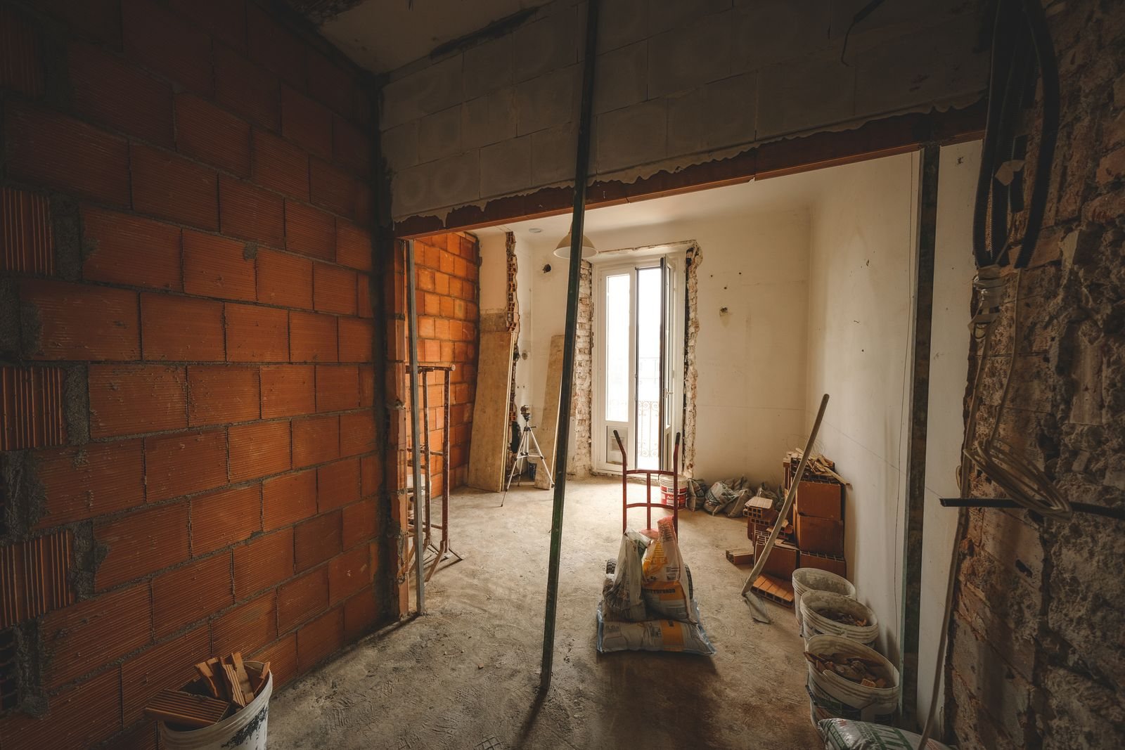 Apartamento em obra, com paredes de blocos cerâmicos ainda sem reboco e material de construção no chão